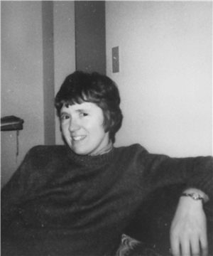 A young white woman with short hair seated and smiling at the camera